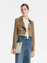 a lady in khaki cropped trench coat with white blouse and jeans